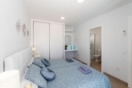 ein Schlafzimmer mit einem Bett mit blauen Kissen darauf in der Unterkunft Amaru in Puerto del Carmen