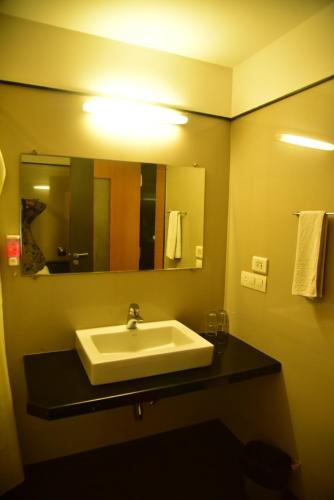 a bathroom with a sink and a mirror and towels at Hi 5 Hotel & Experience in Nashik