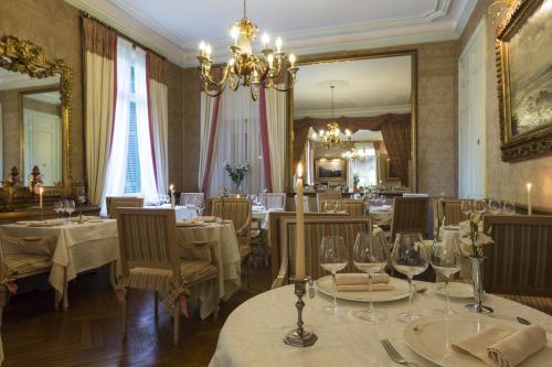 a restaurant with tables and chairs and a chandelier at Belle Isle Sur Risle - Chateau Hotel & Spa in Pont-Audemer