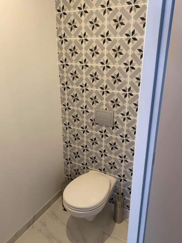 une salle de bain avec toilettes et un mur carrelé dans l'établissement Détente sous les Côtes baignoire balnéo, à Hannonville-sous-les-Côtes