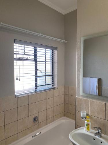 a bathroom with a tub and a sink and a window at Spring Acres Apartment living in Nelspruit
