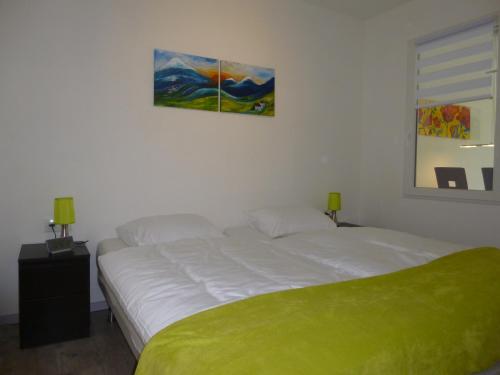 una camera con un letto bianco e una coperta verde di La Konnet a Rougnat