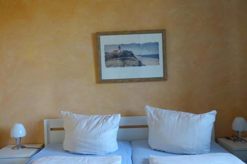 a bedroom with two beds with white pillows and a picture on the wall at De lütte im gulen Hus in Kappeln