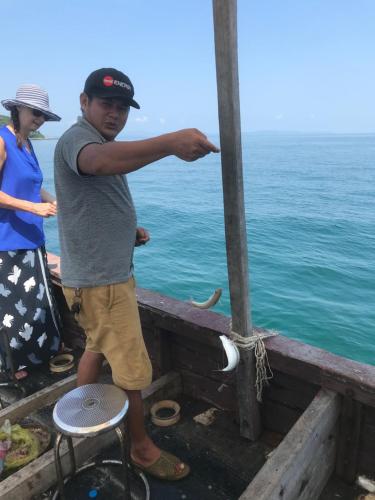 a man standing on a pier pointing at the ocean at Coto Center Homestay in Dao Co To