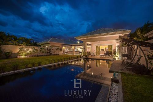 a villa with a swimming pool at night at Cozy Modern 3 Bedroom Pool Villa L70 in Hua Hin