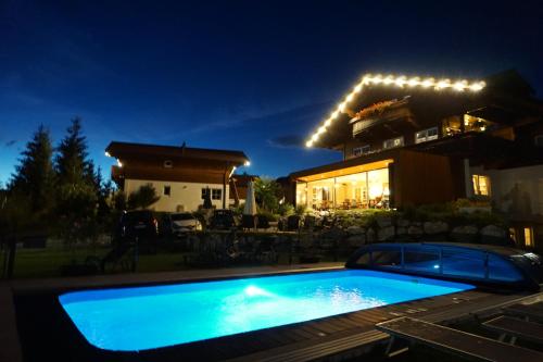 a swimming pool in front of a house at night at Feriendorf Wallenburg in Fieberbrunn