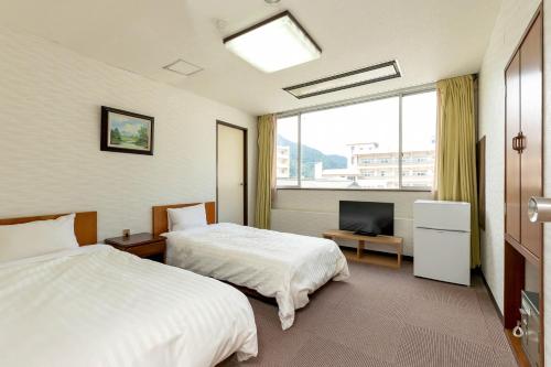 una camera d'albergo con due letti e una televisione di Itoen Hotel New Sakura a Nikko