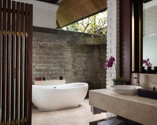 
a white bath tub sitting next to a stone wall at Tanah Gajah, a Resort by Hadiprana in Ubud
