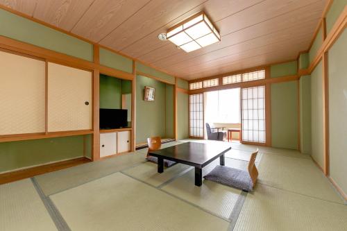 un soggiorno con tavolo e TV di Itoen Hotel New Sakura a Nikko