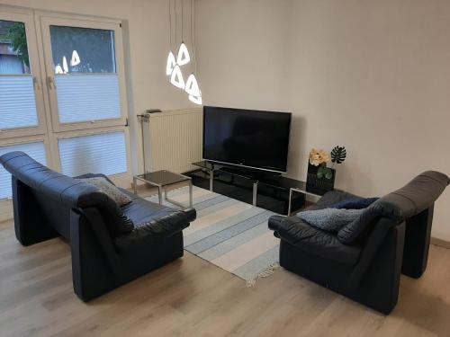 a living room with two couches and a flat screen tv at Ferienwohnung Haus Gards in Marpingen