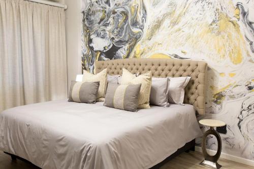 a bedroom with a white bed with a painting on the wall at Melville Gap Guesthouse in Johannesburg