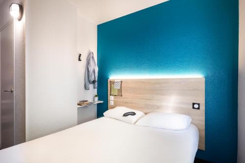 a white bed in a room with a blue wall at hotelF1 Paris Gennevilliers, 4 Rue Georges Corète 92230 Gennevilliers in Gennevilliers