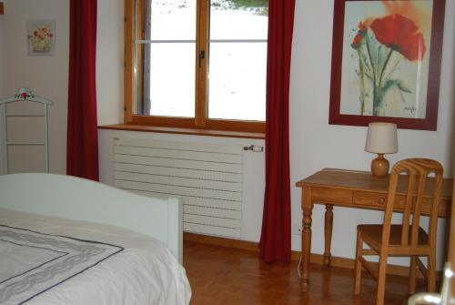 a bedroom with a bed and a desk and a window at Chambre d'hôtes Kieffer Le Grand Bienfaisy in Remiremont
