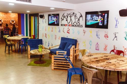 a room with tables and chairs and a tv on the wall at BcnSportHostels in Barcelona
