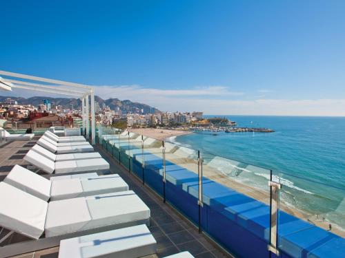 a view of a beach with white umbrellas and the ocean at Hotel Villa del Mar in Benidorm