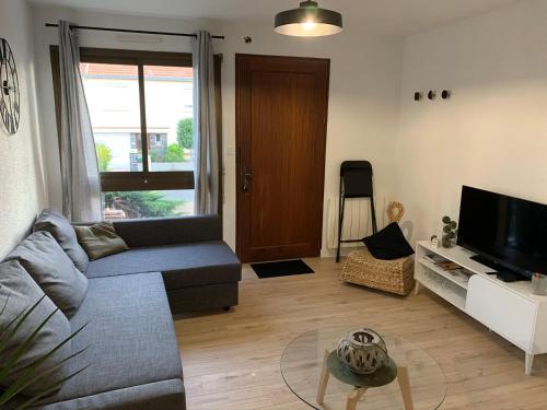 a living room with a couch and a tv at Logement rénové et moderne au Sacré Coeur Cholet in Cholet