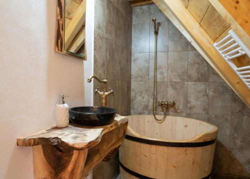 a bathroom with a wooden tub and a sink at Casa Bunicilor Apuseni in Geogel