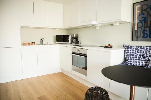 a kitchen with white cabinets and a table and a microwave at Frogner House Apartments - Huitfeldtsgate 19 in Oslo
