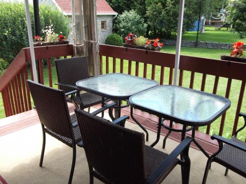 een groep tafels en stoelen op een veranda bij Au Gîte de la Chute in Boischâtel