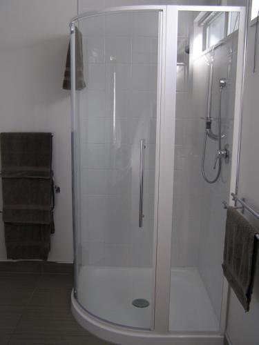 a shower with a glass door in a bathroom at Bellano Motel Suites in Christchurch