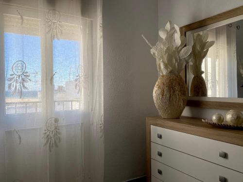 Habitación con ventana y tocador con jarrón en Piso en Conil con Vistas al mar en Conil de la Frontera