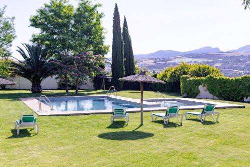 einen Garten mit einem Pool mit Stühlen und einem Sonnenschirm in der Unterkunft Hotel Boutique Molino del Arco in Ronda