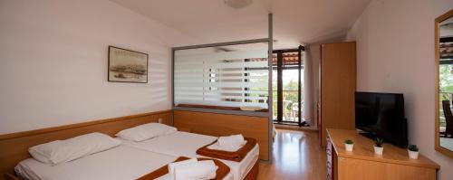 a bedroom with a bed and a flat screen tv at Apartments Hostin Roža Duga Uvala in Krnica
