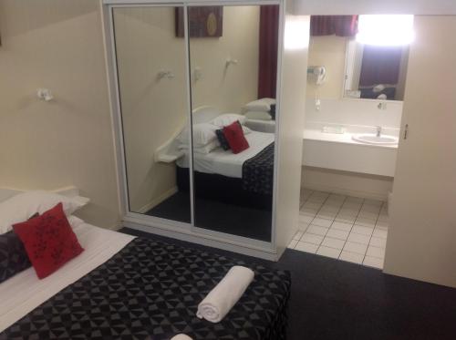 a room with a bathroom with a bed and a sink at Parkside Motel Ayr in Ayr