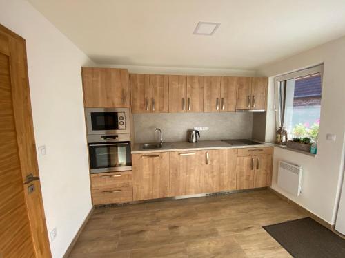 an empty kitchen with wooden cabinets and a window at Rodinný penzion Kohoutek in Hovorany