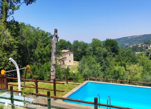 einen Pool in einem Garten mit einem Holzzaun in der Unterkunft Country House Antiche Dimore in Abbateggio