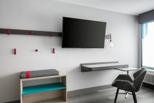 a room with a bed and a tv on a wall at Avid Hotels - Roseville - Minneapolis North by IHG in Roseville