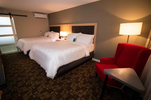 a hotel room with two beds and a red chair at Holiday Inn Scranton East - Dunmore, an IHG Hotel in Dunmore