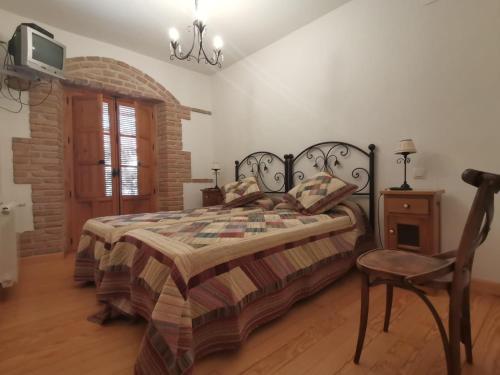 1 dormitorio con 1 cama, 1 silla y TV en La Aldaba del siglo XX, en Alcañizo