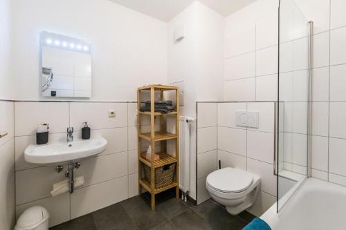 een witte badkamer met een toilet en een wastafel bij Ferienwohnung Alte Baumwollspinnerei in Leipzig