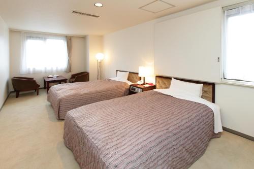 a hotel room with two beds and a window at Hotel Green Park in Sendai