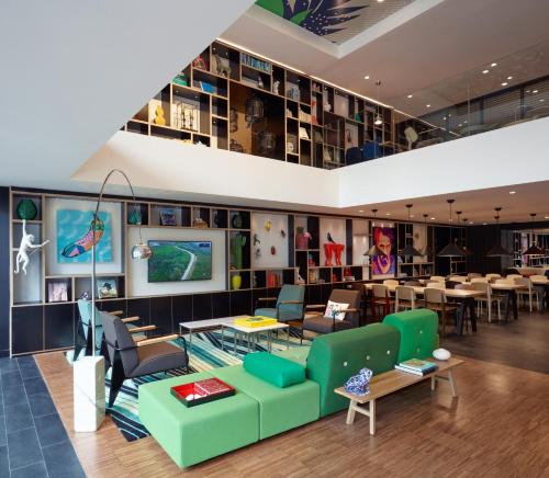 a lobby with a green couch and tables and chairs at citizenM Kuala Lumpur Bukit Bintang in Kuala Lumpur