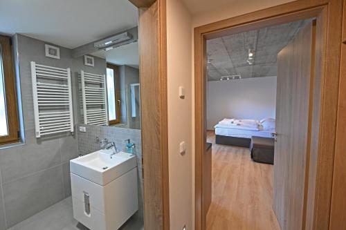 uma casa de banho com um lavatório e um quarto com uma cama em Vetrnik Depandance Hotelu Jirinka em Dolní Morava