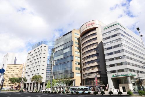 a large building with a bus parked in front of it at Hotel Premium Green Hills in Sendai