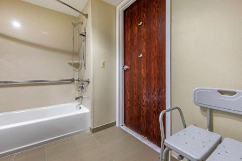 a bathroom with a bath tub and a wooden door at Comfort Suites Visalia - Convention Center in Visalia