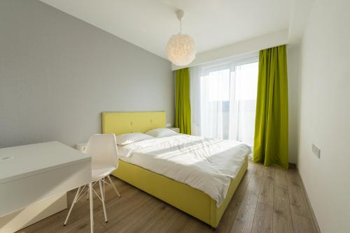 a bedroom with a bed and a desk and a window at ART Apartment in Târgu-Mureş