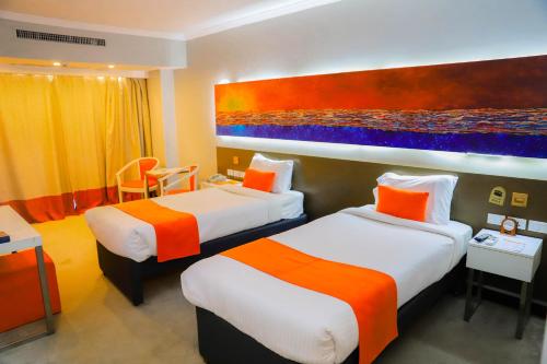 Citymax Hotel Aswan في أسوان: غرفة فندقية بسريرين ولوحة على الحائط