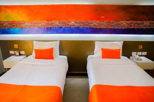 two beds in a room with a painting on the wall at Citymax Hotel Aswan in Aswan
