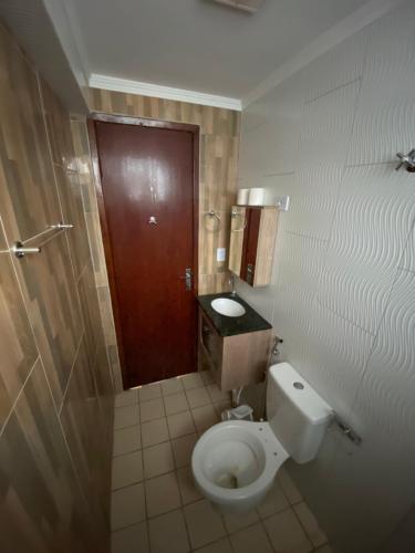 a bathroom with a toilet and a brown door at Boss Apartments in Paranoá