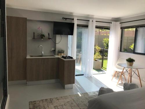 uma cozinha com um lavatório e uma mesa num quarto em Blouberg Studio Apartment em Bloubergstrand