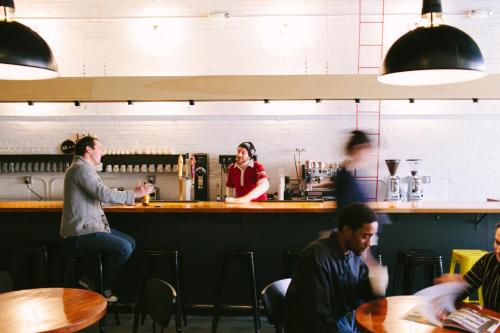 a group of people sitting at a bar at The Local NY in Queens