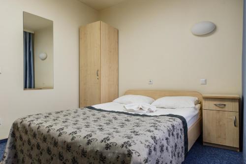1 dormitorio con 1 cama y armario de madera en East Time Hotel, en Minsk
