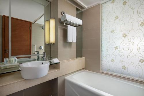 a bathroom with a sink and a tub and a mirror at Holiday Inn Chengdu Century City-EastTower in Chengdu