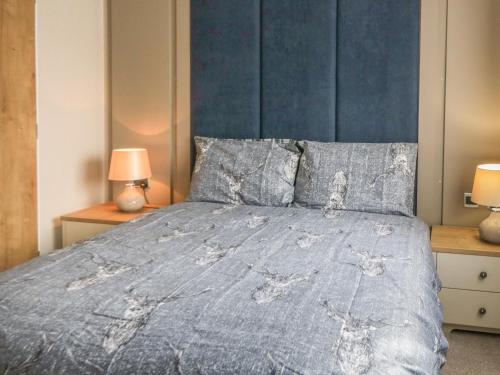a bedroom with a bed with a blue headboard and two lamps at Daisy Lodge in Scarborough