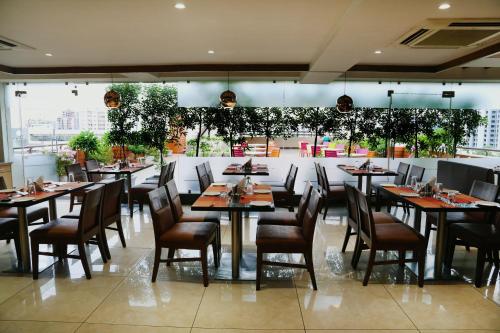 un restaurante con mesas y sillas y una gran ventana en The Park Residency, en Ahmedabad