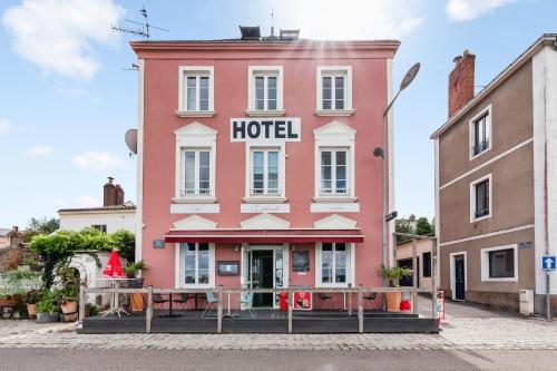 a pink hotel with tables in front of it at L'Esplanade in Le Pellerin